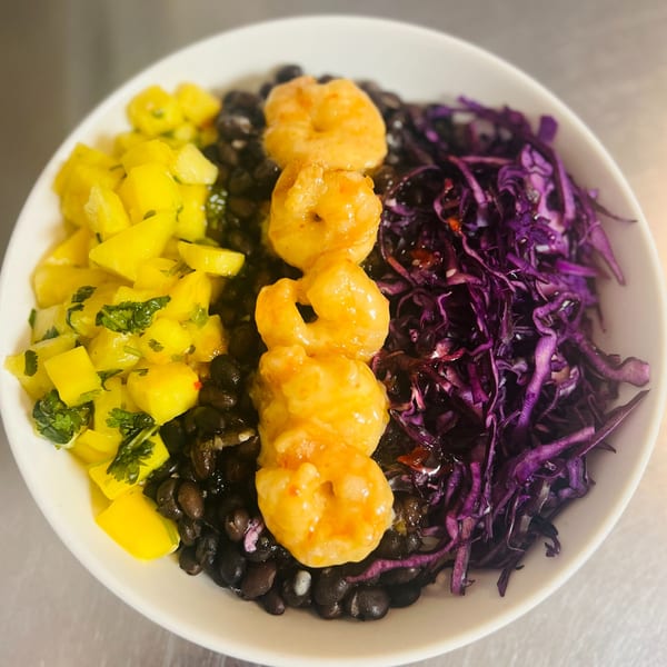 A colorful Fat Fish Taco bowl with shrimp, black beans, mango salsa, and purple cabbage.