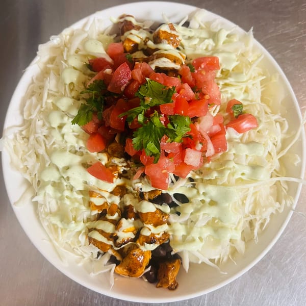Fat Fish Taco's Mexican bowl with shredded cabbage, black beans, chicken, tomatoes, and creamy sauce.