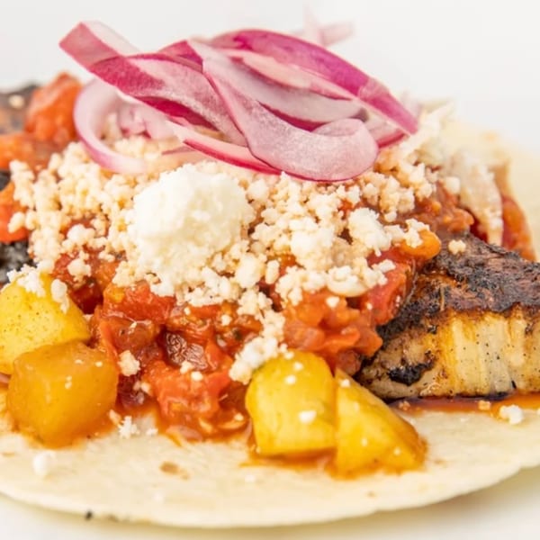Fat Fish Taco's grilled fish taco with pineapple, salsa, cheese, and red onions.